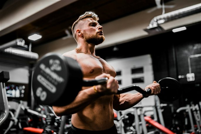 Hombre levantando un peso en un gimnasio para entrenar su fuerza y resistencia muscular.