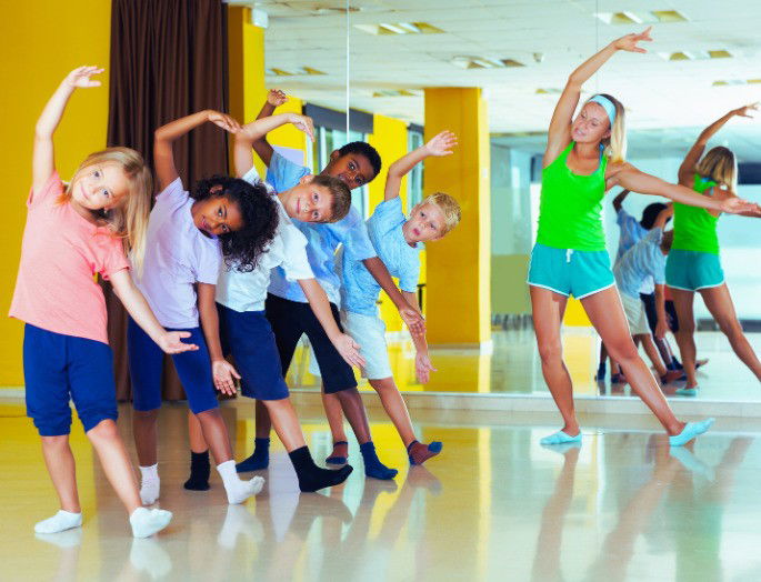 niños practicando movimientos de baile en un aula frente al espejo