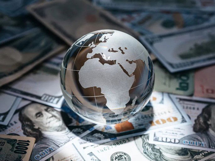 economía: globo terráqueo de vidrio posado encima de dinero