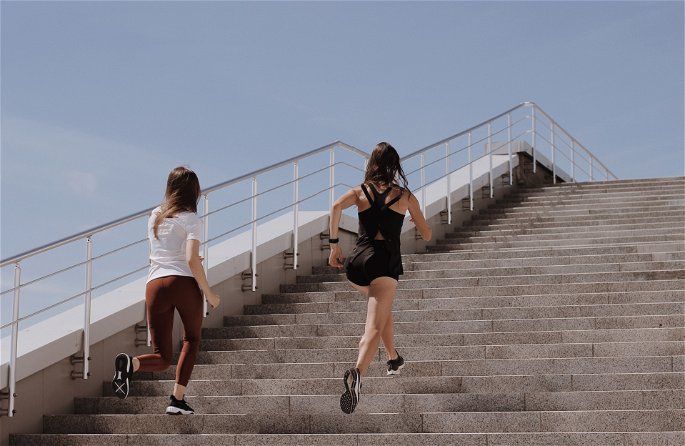 Dos mujeres ejercitando su fuerza de resistencia corriendo por las escaleras