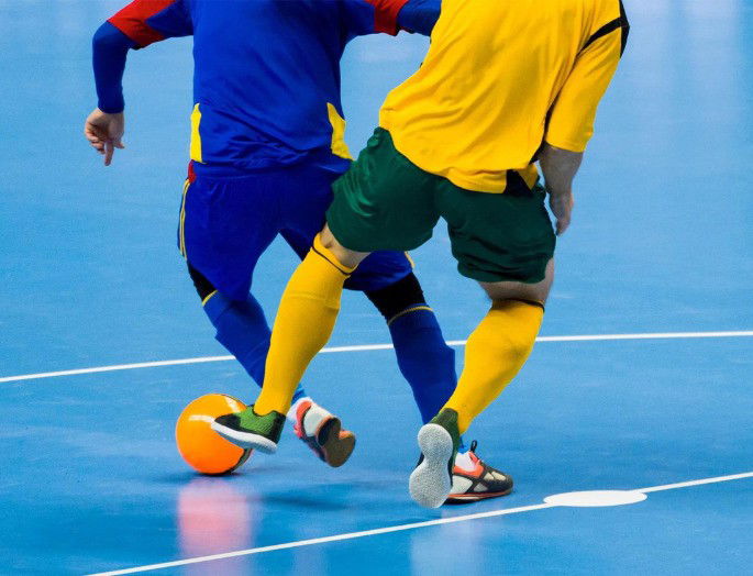 Dos jugadores de fútbol sala con el balón en la cancha