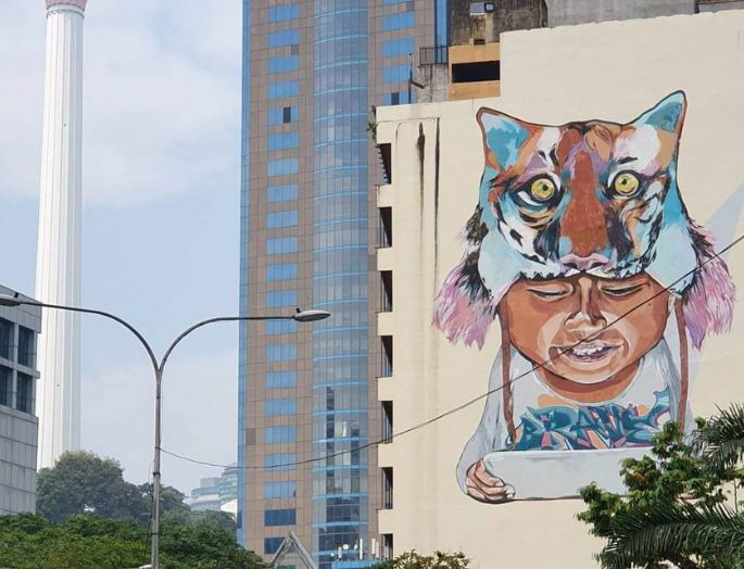 Grafiti en la ciudad de Kuala Lumpur, en la que aparece un niño leyendo, con un gorro de gato.