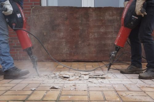 Dos personas usando taladros en el suelo de un edificio, lo que provoca contaminación acústica