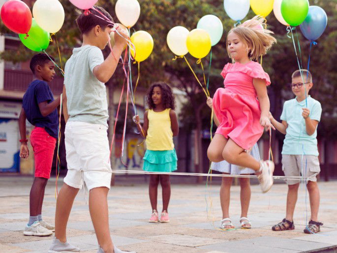 niños jugando a la goma en la calle