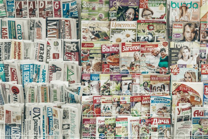 Conjunto de periódicos y revistas colocados en un quiosco para su venta.