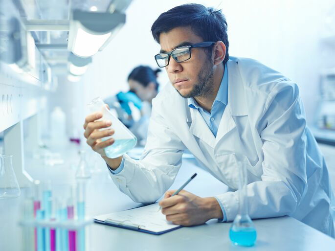 Una persona siguiendo el método científico en un experimento del laboratorio, analizando una muestra y tomando notas