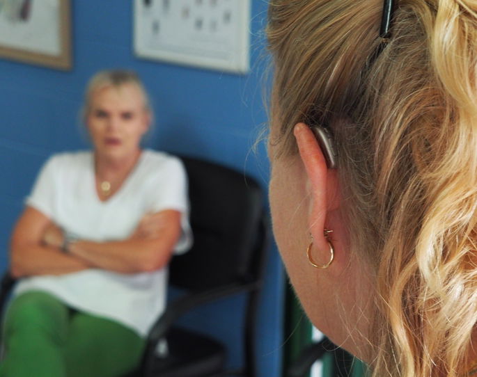 Mujer con audífono hablando con otra - Consecuencia de contaminación acústica