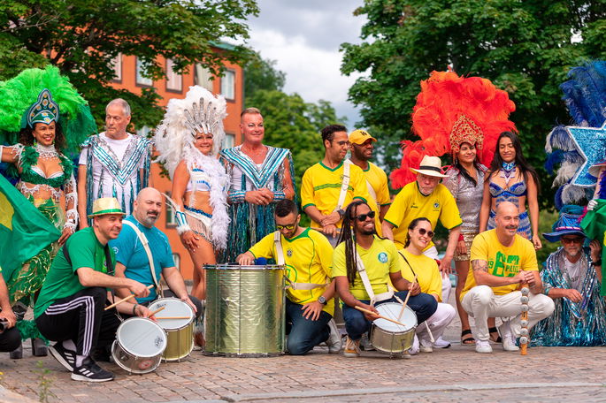 Grupo de samba posando con trajes de carnaval y camisetas de Brasil