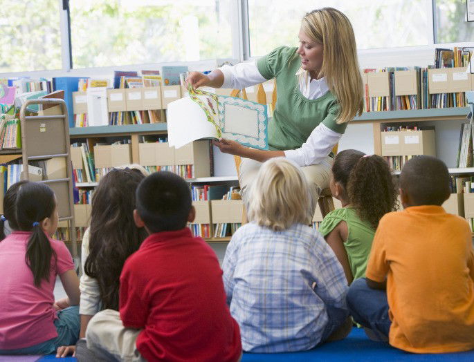 Profesora leyendo a un grupo de niños en la biblioteca