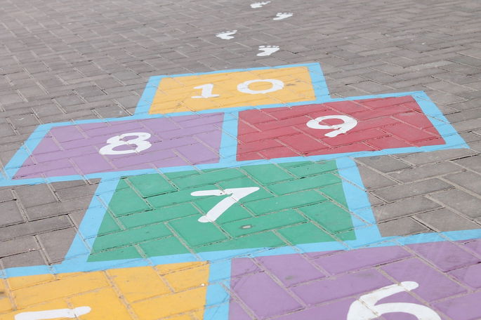 tablero de juego de rayuela pintado en la calle, con casillas de colores.