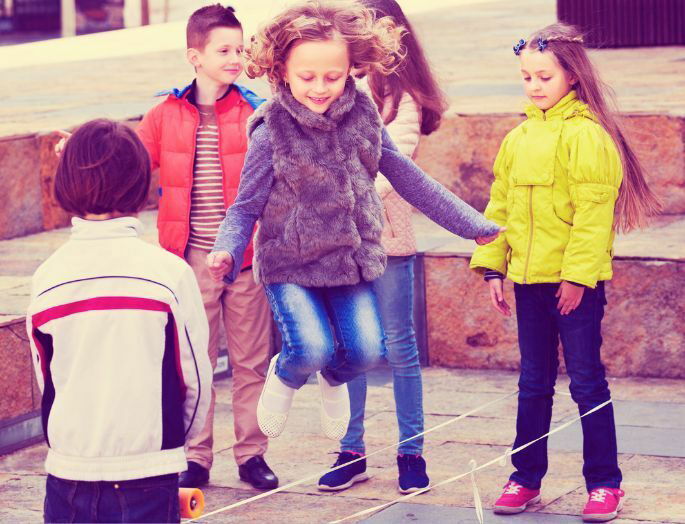 Juego tradicional saltar a la goma. Varios niños juegan.