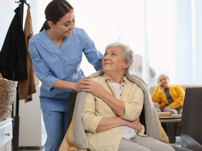 Una joven cuidado de una persona mayor en una residencia para mayores