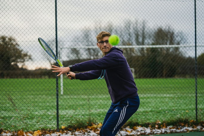 Un joven jugando a tenis, aplicando flexibilidad dinámica en la actividad