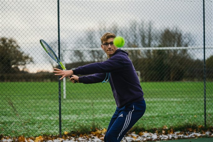 Un joven jugando a tenis, aplicando flexibilidad dinámica en la actividad