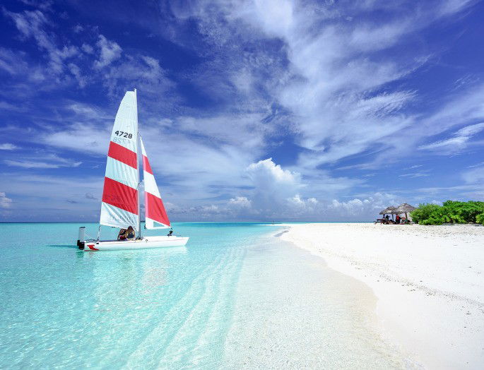 imagen de una playa en verano con velero