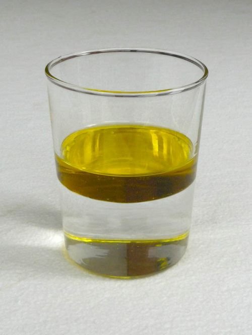 Una copa de aceite y agua líquida, separados por la variación en densidad